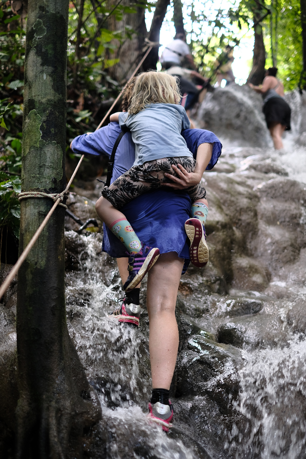 Familienfotografie Berlin - Mutter tr&auml;gt Kind den Wasserfall hinauf