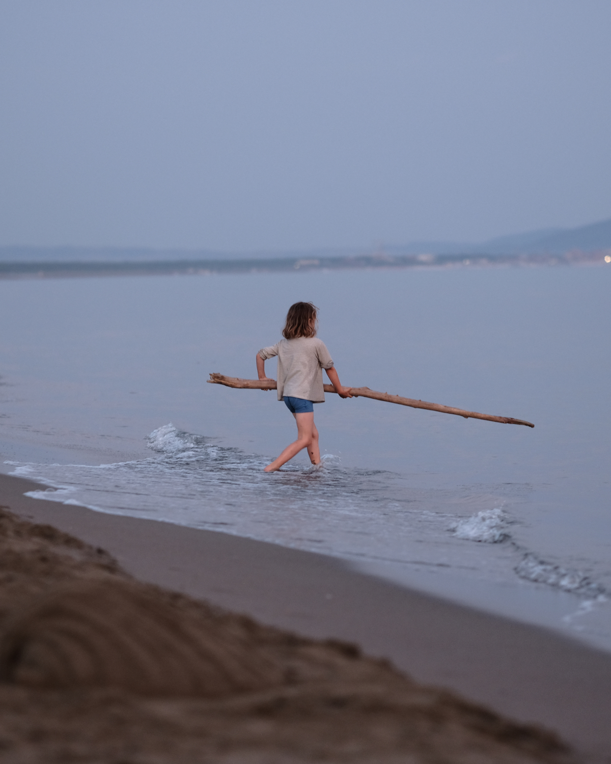 Kind mit Stock am Abendstrand