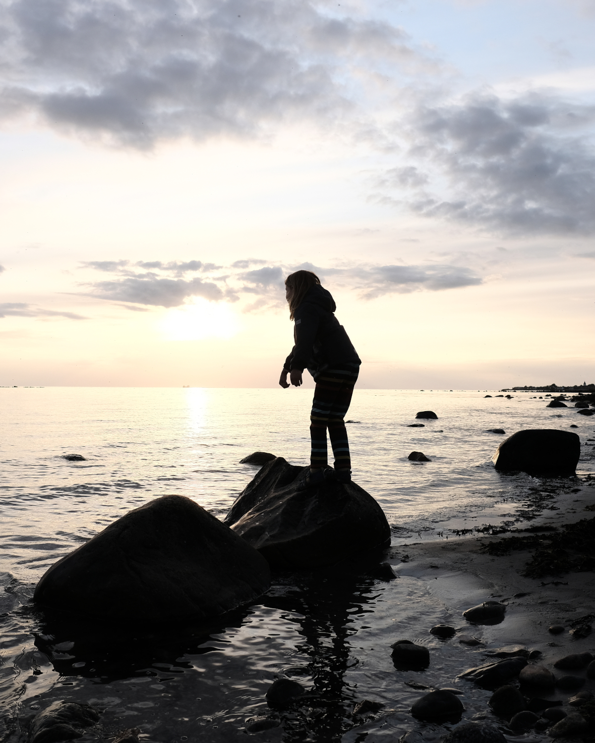 Kind auf Felsen im Sonnenuntergang